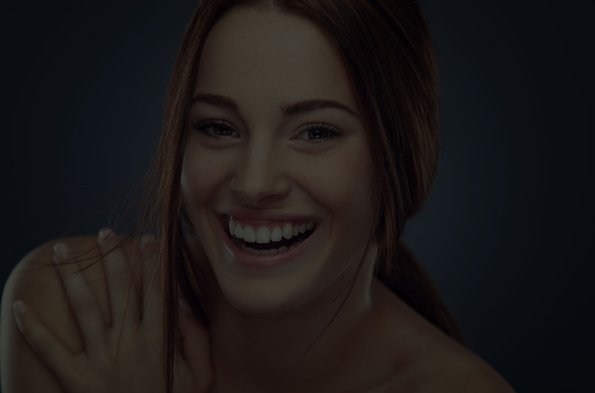 Woman with brown hair smiling with smooth skin and symmetric features.